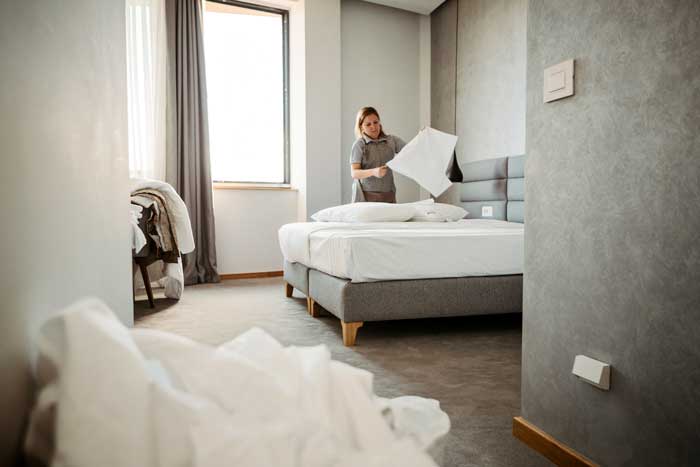 Kvinna bäddar säng på ett hotell.